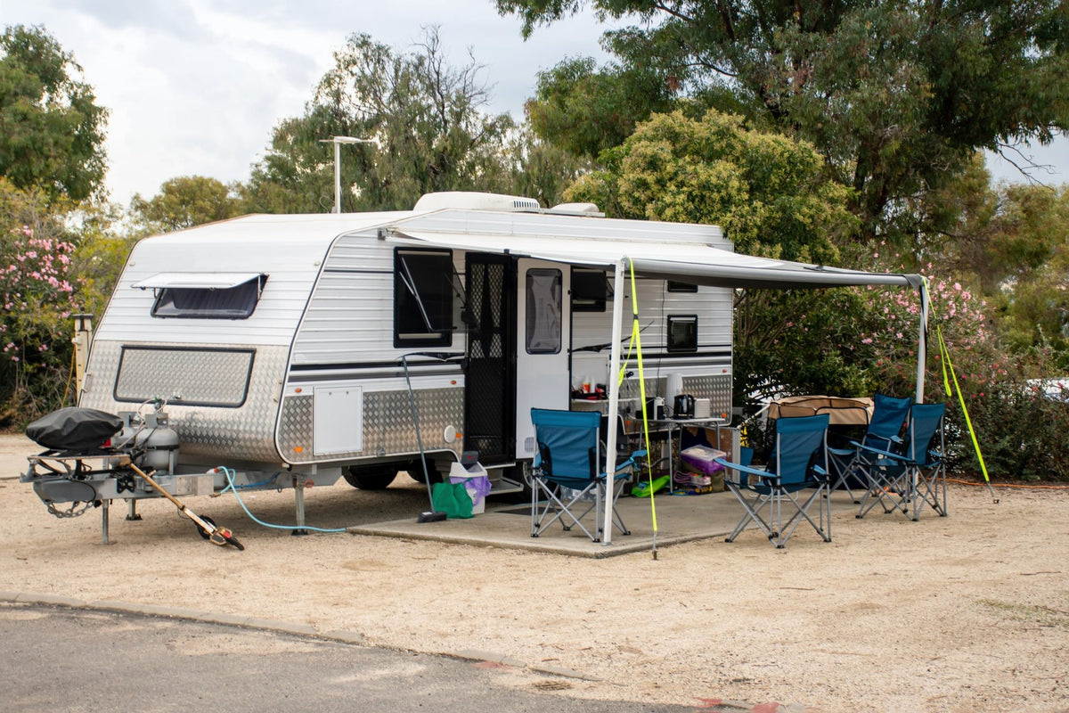 Caravan with an awning and camp chairs set up on a site at a caravan park